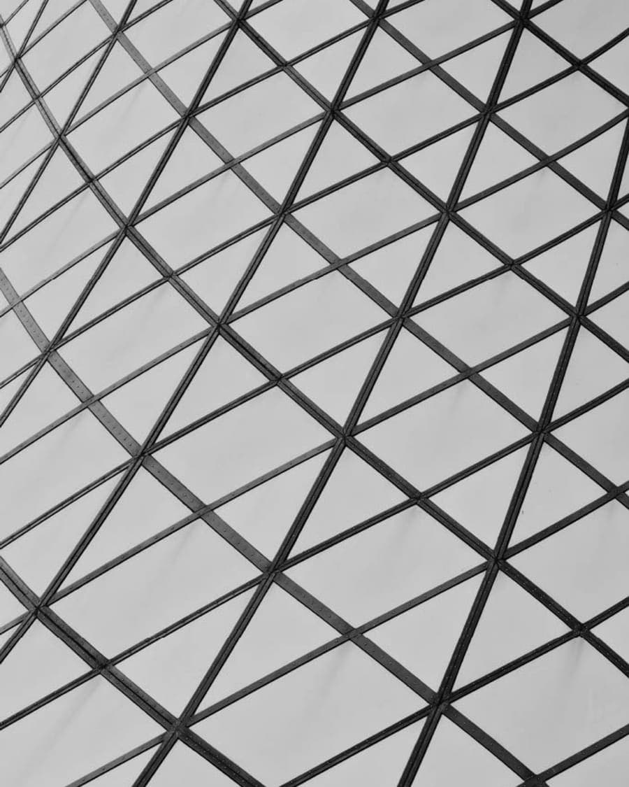 Detalle arquitectónico en blanco y negro, estructura triangular de vidrio y acero